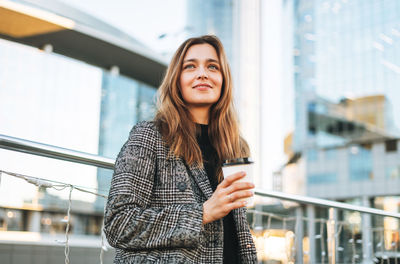 Portrait of young woman standing in city