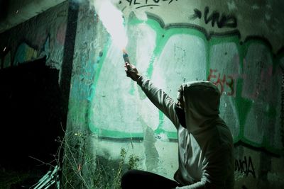 Side view of man holding graffiti on wall