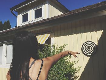 Rear view of young woman throwing dart