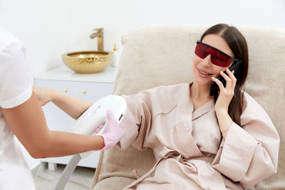 Young woman using mobile phone while sitting at home