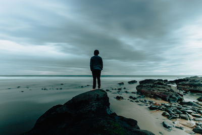 Rear view of man looking at sea against sky