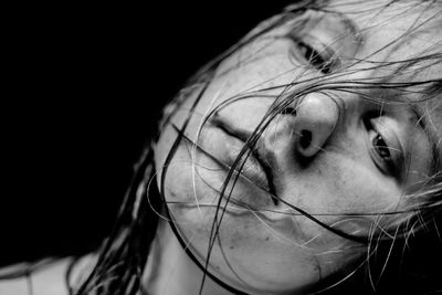 Close-up of young woman against black background