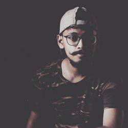 Portrait of young man wearing cap and eyeglasses in darkroom