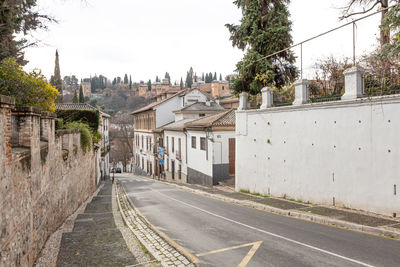 Empty road by buildings against sky