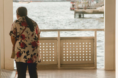 Rear view of woman standing by railing