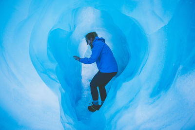 Side view of woman standing in ice cave