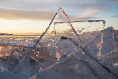 Close-up of icicles on beach against sky during sunset