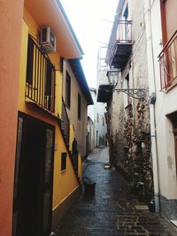 Alley amidst houses against sky