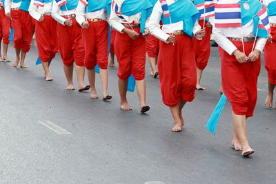 Low section of women in traditional clothing with flags walking on street in city