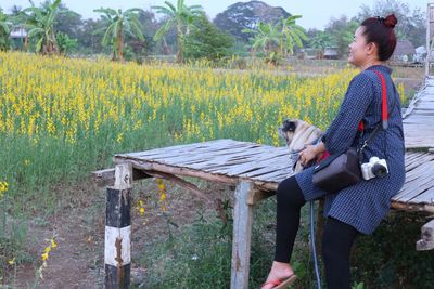 Woman sitting with dog on wood by plants