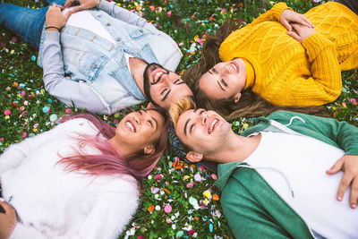 High angle view of cheerful friends lying on grassy land