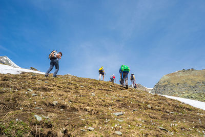 Low angle view of people on mountain against sky