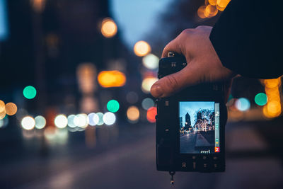 Person photographing illuminated smart phone at night