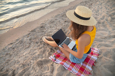 High angle view of woman using laptop on beach