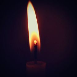 Close-up of lit candle in dark room