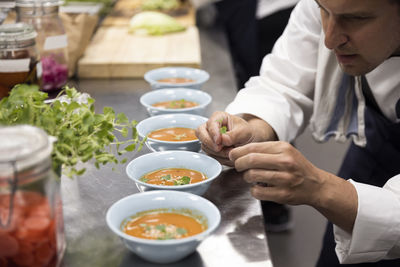 Chef garnishing soup at kitchen counter in restaurant