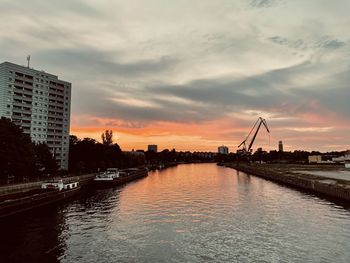 River by buildings against sky during sunset