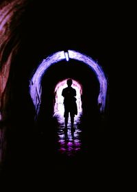 Rear view of silhouette man standing in tunnel