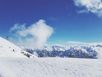 Scenic view of snow covered mountains against blue sky