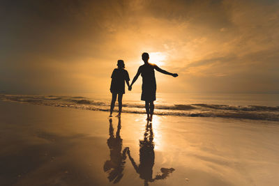 Silhouette asian couple holding hand with happiness and joyful from honeymoon activity in summer