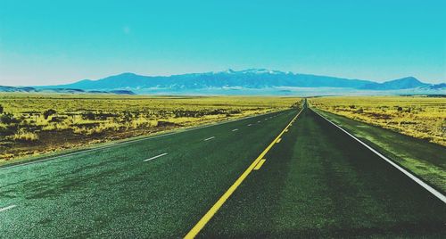 Road leading towards mountains against sky