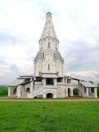 Church on field by building against sky