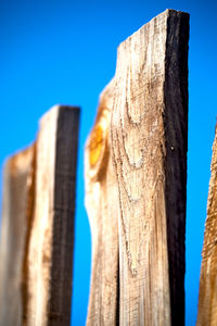 Low angle view of wooden post against clear blue sky