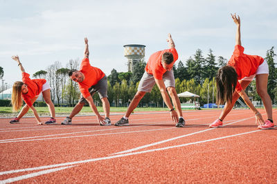 Athletes exercising on sports track against sky