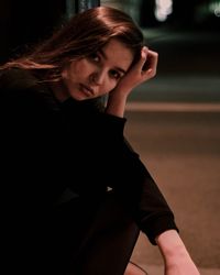 Portrait of young woman sitting outdoors at night