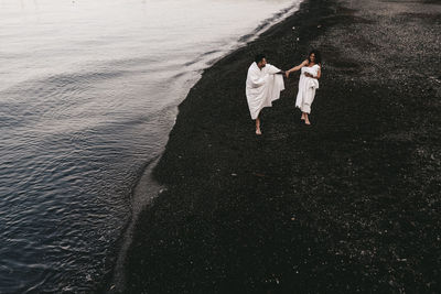 A diverse of lovers a man and a woman embrace under a blanket on the ocean at night outdoor