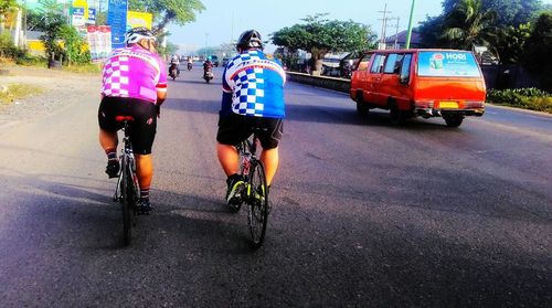 Rear view of boy riding bicycle on street