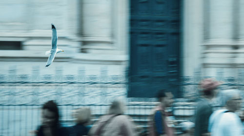 Blurred motion of people walking by building