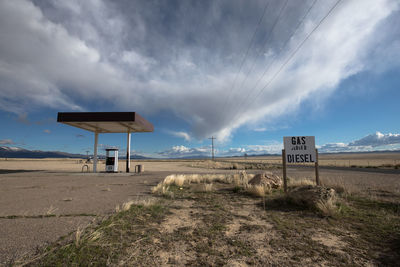 Gas station at remote area against cloudy sky