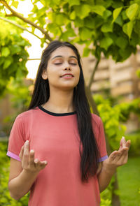 Portrait of young woman standing against plants