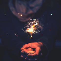 Midsection of woman holding lit sparkler