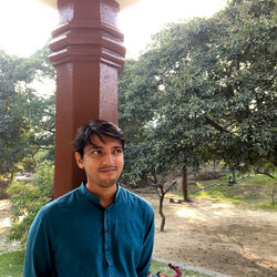 Portrait of young man standing against trees