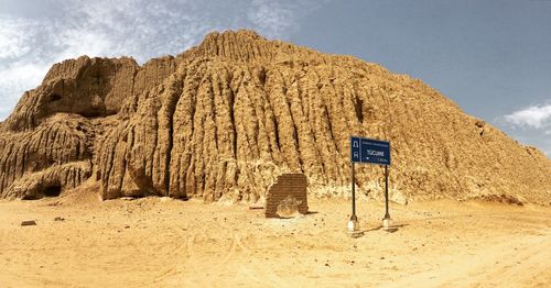 Information sign on desert against sky