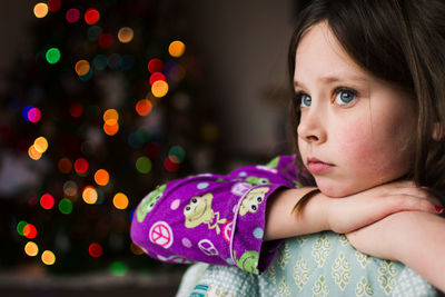 Close-up of girl looking away against illuminated lights at home