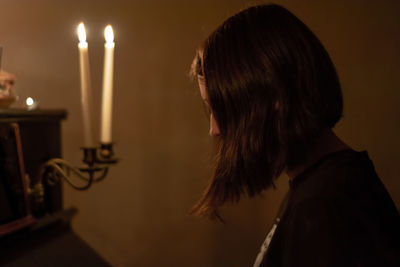 Portrait of woman against illuminated candles