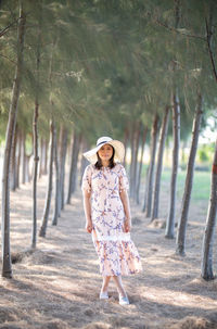 Portrait of woman standing amidst trees at beach