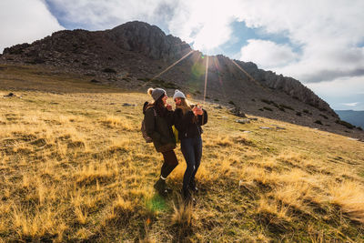 People on field by mountain against sky