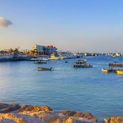 Boats moored in sea against clear sky