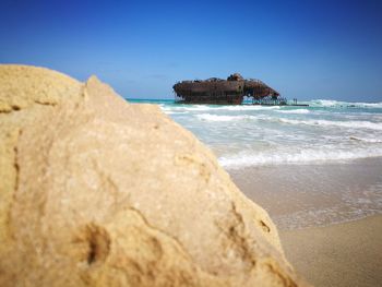 Rock formations on beach against clear blue sky