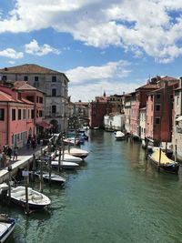 Boats moored in canal amidst buildings in city