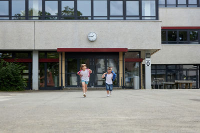 Full length of kids running in front of school building