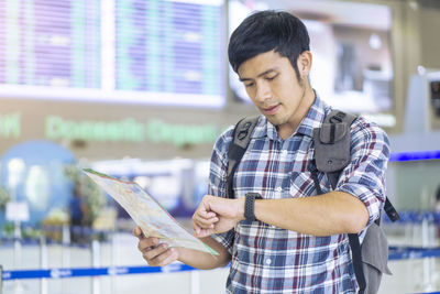Man checking time while standing at airport departure area