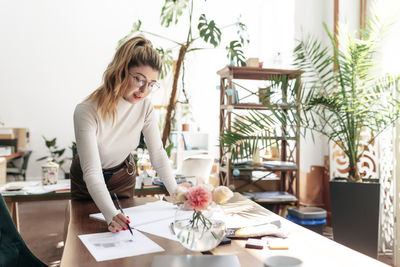 Young woman with potted plants on table