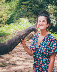 Smiling young woman holding elephant trunk