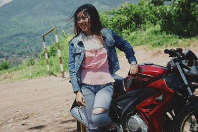 Smiling woman standing by motorcycle