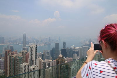 Midsection of man using mobile phone against sky